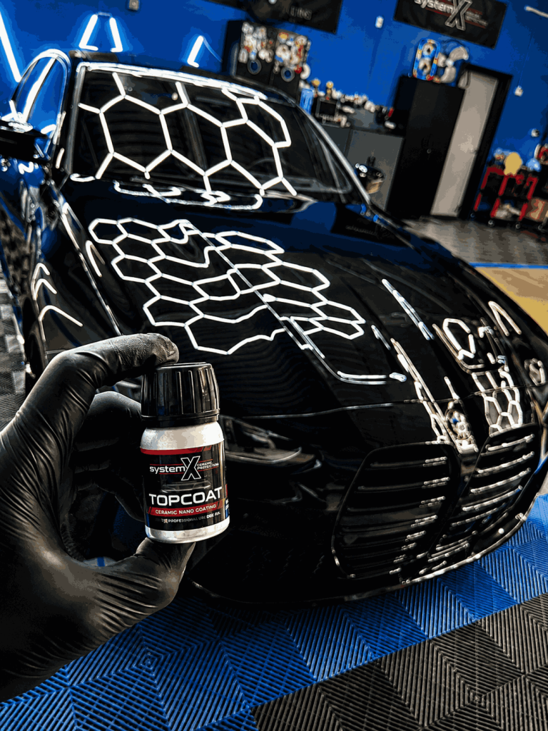 Gloved hand applying System X Topcoat ceramic nano coating to a Mercedes hood in Prestige Detailing shop